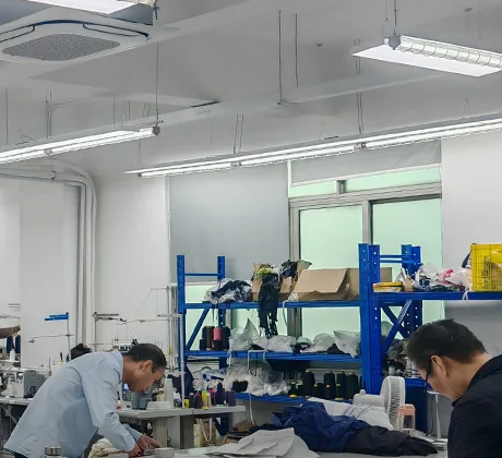 A workroom with cutting tables, blue boltless racking and two people working at a table