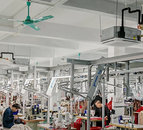 Rows of industrial sewing machines with workers seated at the machines